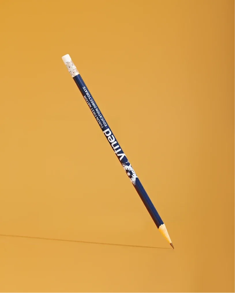 Blue YFNED wooden pencil with a white eraser, floating diagonally on a gold background.